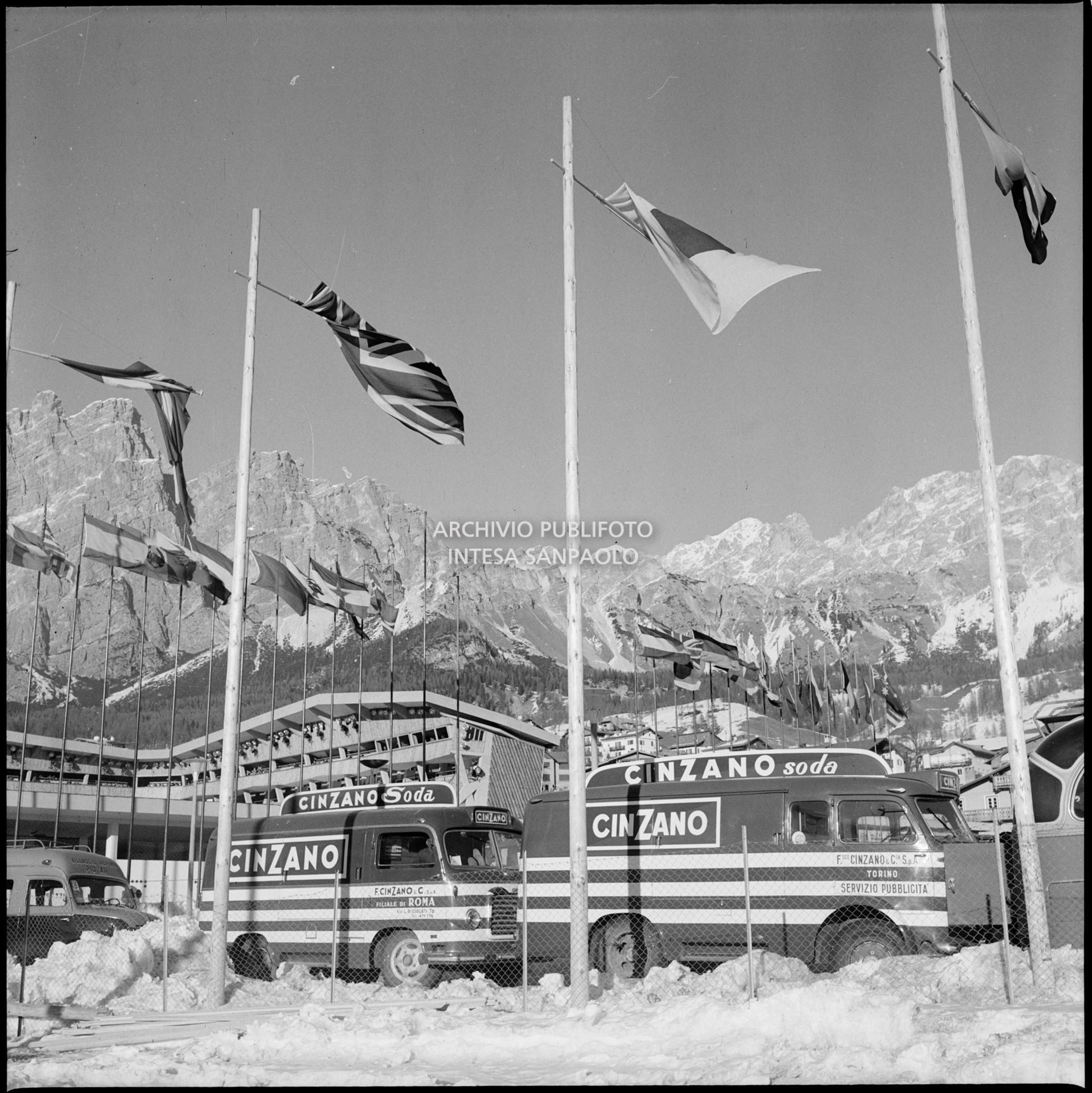 Furgoni pubblicizzano il Cinzano Soda a Cortina d'Ampezzo nei giorni dei VII Giochi olimpici invernali; sullo sfondo lo Stadio del ghiaccio