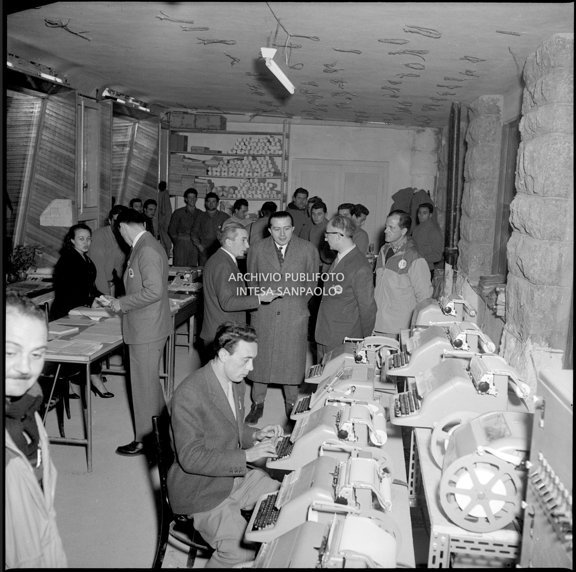 Il ministro delle Finanze Giulio Andreotti vista il reparto telescriventi del Centro per la stampa a Cortina d'Ampezzo; alla sua sinistra, Giuseppe Sabelli Fioretti, direttore del Centro