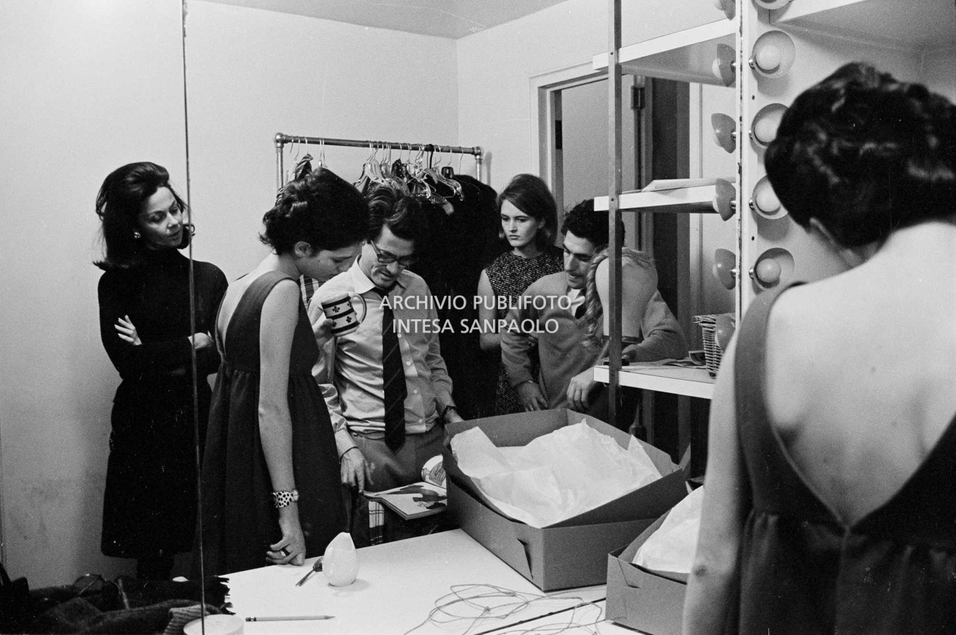 Benedetta Barzini, Richard Avedon e alcuni collaboratori guardano una rivista in camerino