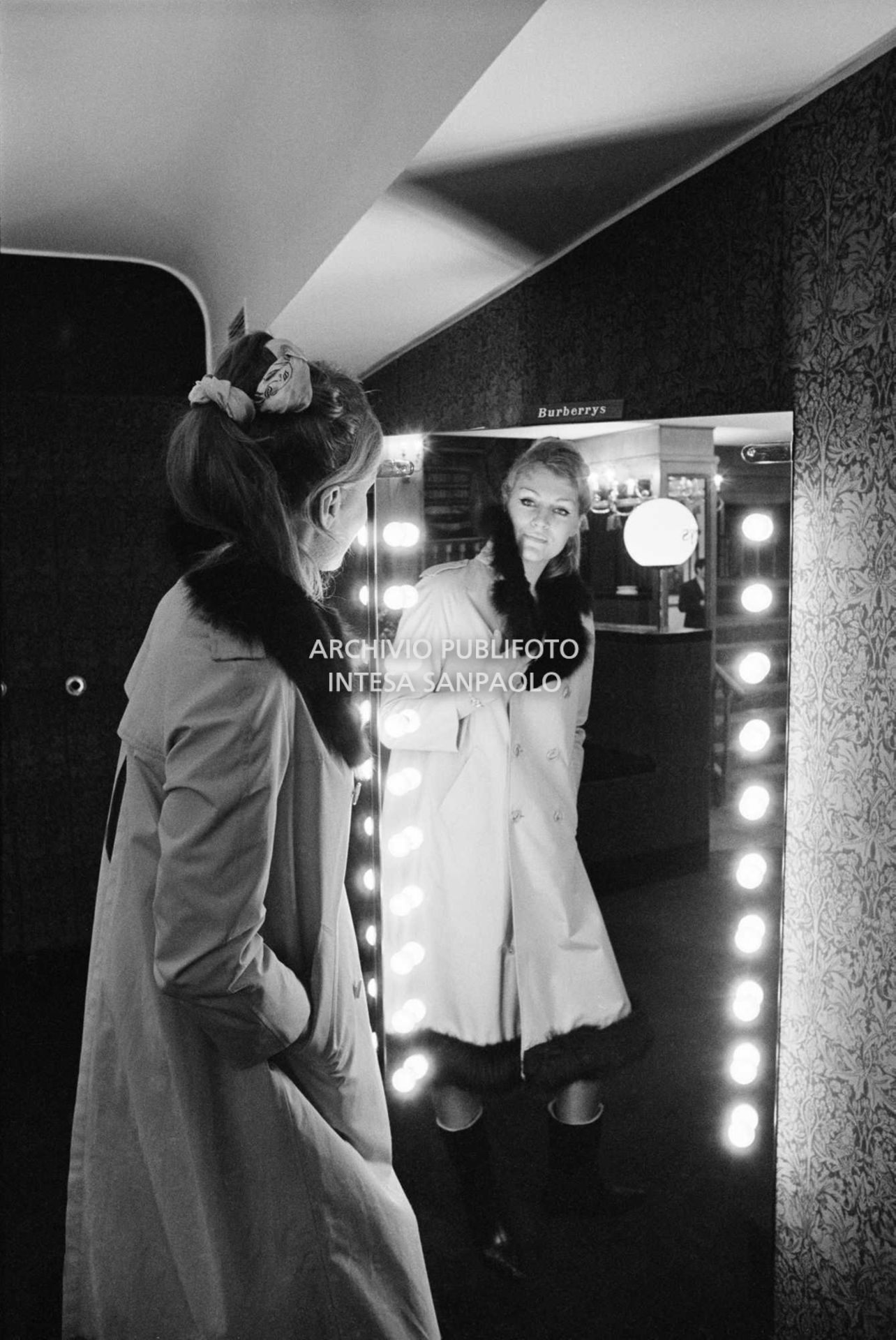 Anna German, con indosso un trench con l'interno in pelliccia, si specchia al negozio Burberrys'