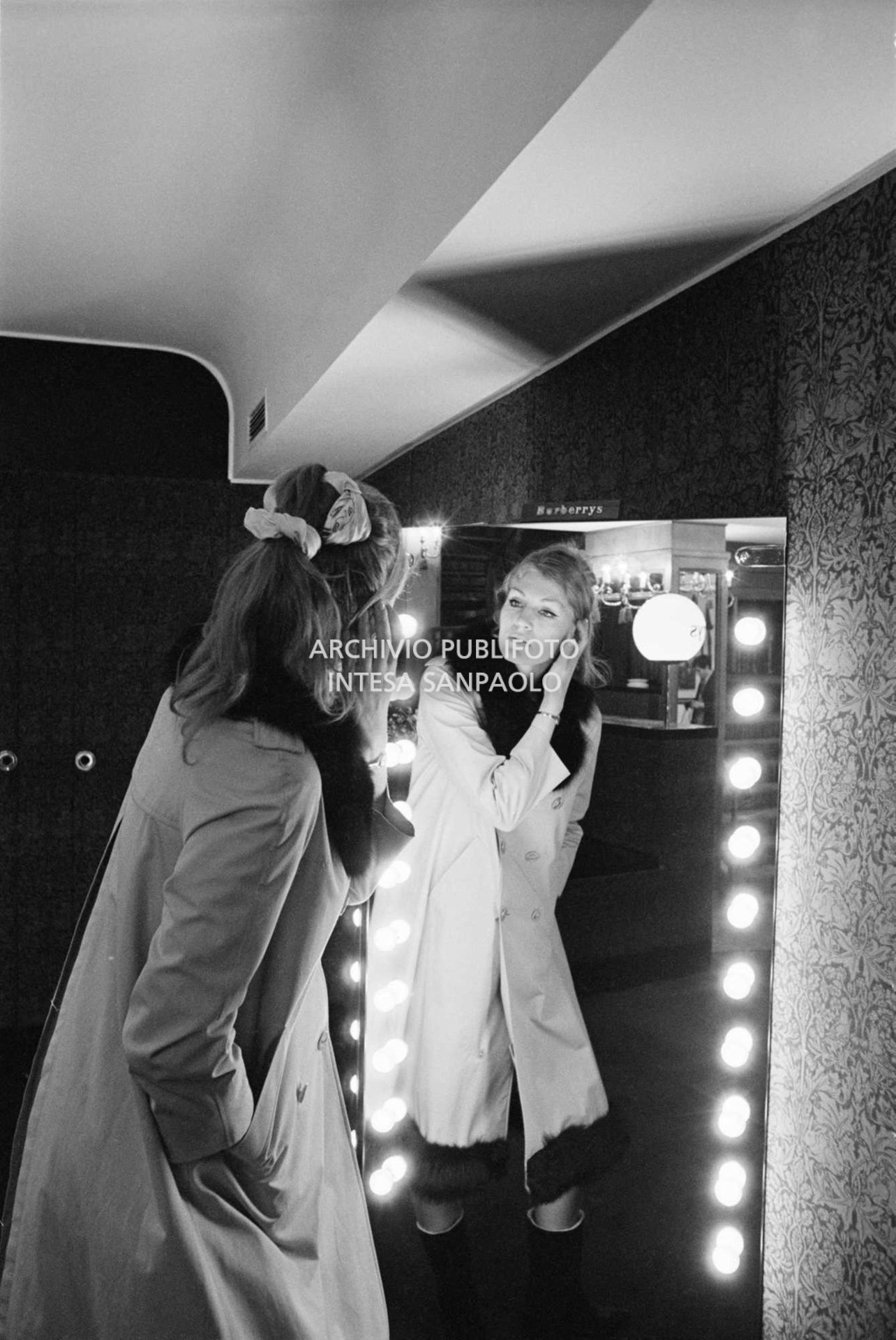 Anna German, con indosso un trench con l'interno in pelliccia, si specchia al negozio Burberrys's'