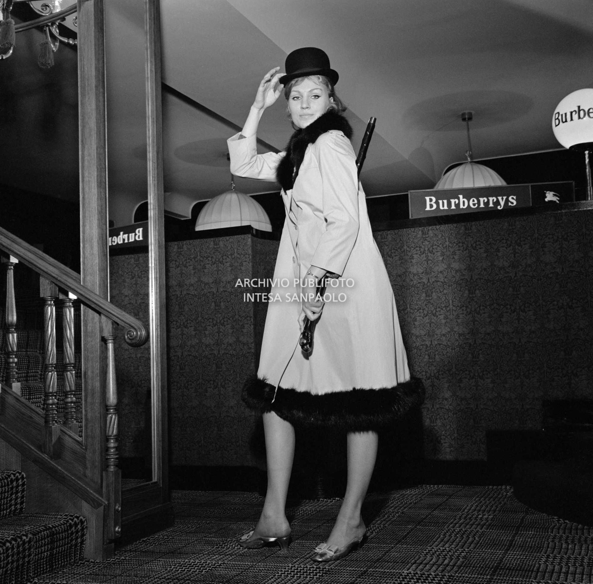 Anna German in posa con bombetta e trench, con interno in pelliccia, al negozio Burberrys'