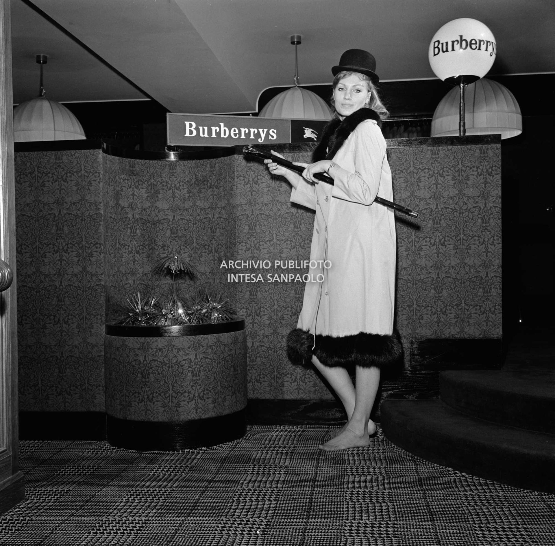 Anna German in posa con bombetta e trench, con interno in pelliccia, al negozio Burberrys'