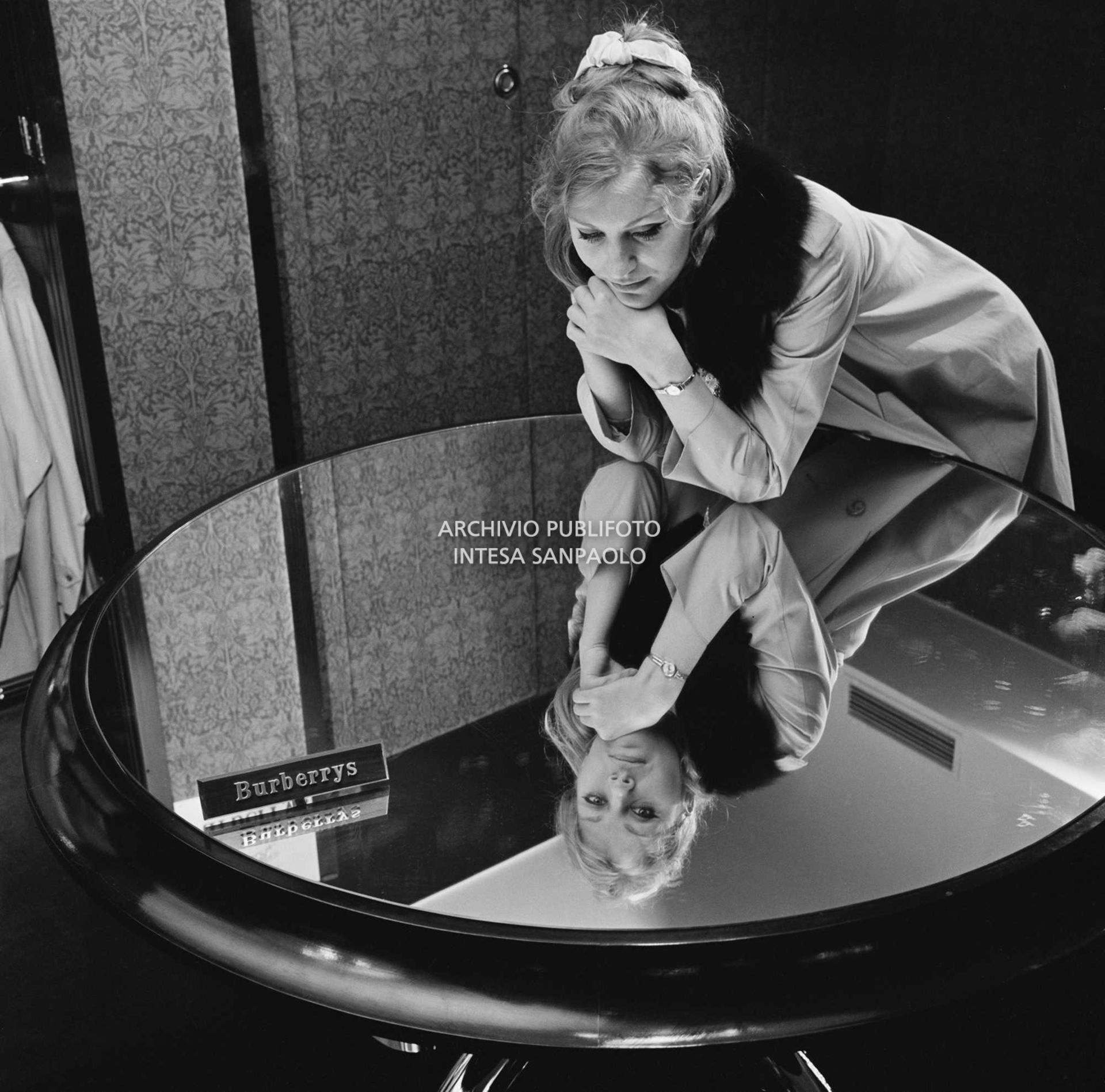 Anna German, con indosso un trench con l'interno in pelliccia, si specchia in un tavolino al negozio Burberrys'