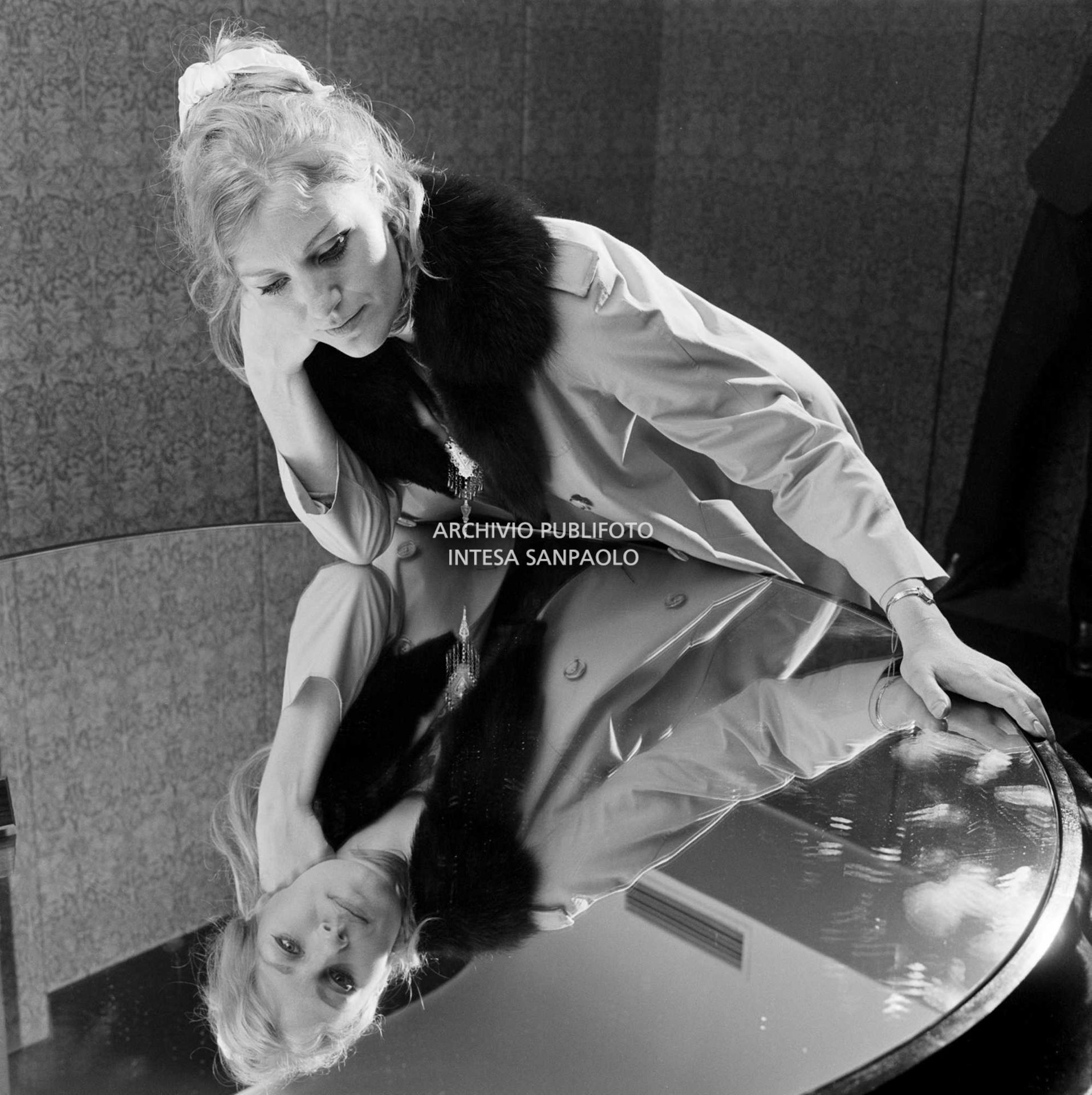 Anna German, con indosso un trench con l'interno in pelliccia, si specchia in un tavolino al negozio Burberrys'