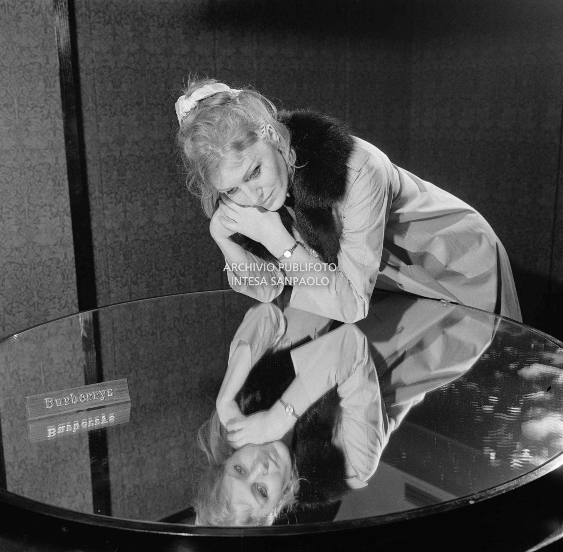 Anna German, con indosso un trench con l'interno in pelliccia, si specchia in un tavolino al negozio Burberrys'