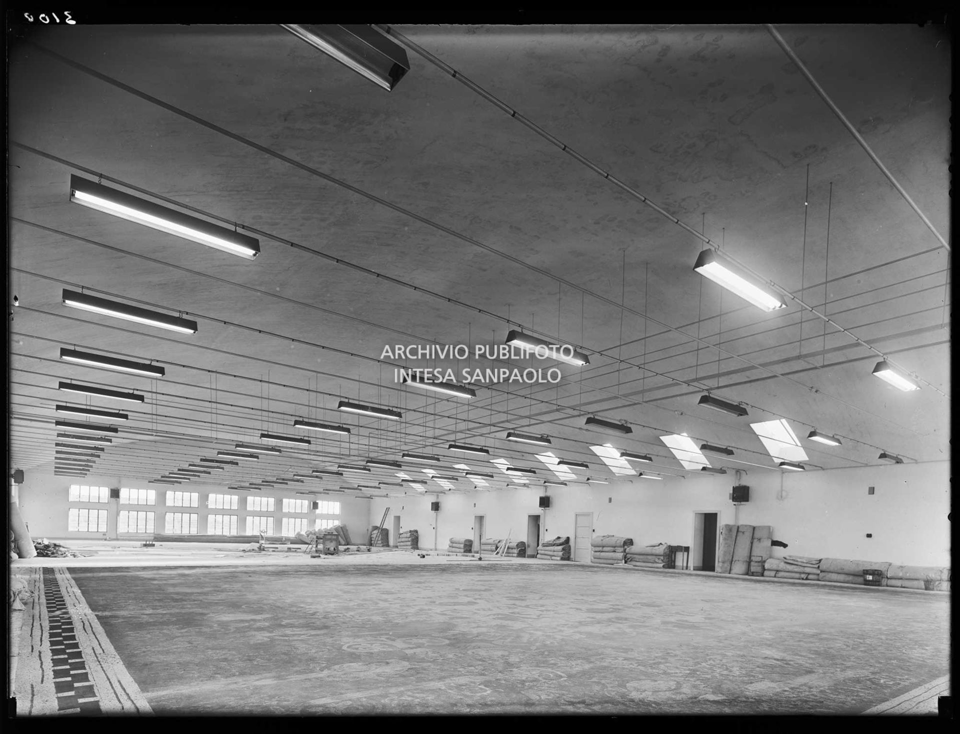 Veduta di un laboratorio della sezione scenografia del Teatro alla Scala di Milano. Addossati ai muri materiali di lavoro, per terra un fondale in lavorazione