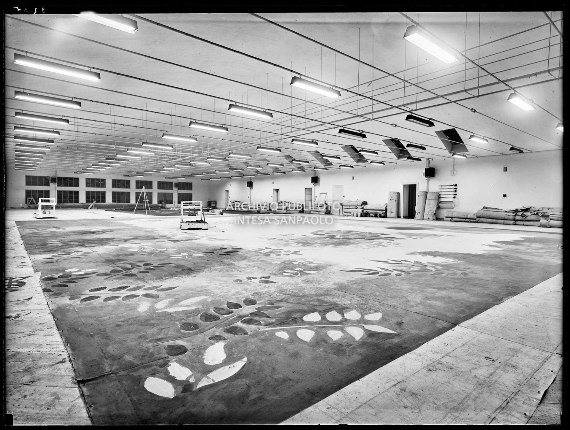 Veduta di un laboratorio della sezione scenografia del Teatro alla Scala di Milano. Addossati ai muri materiali di lavoro, per terra un fondale in lavorazione