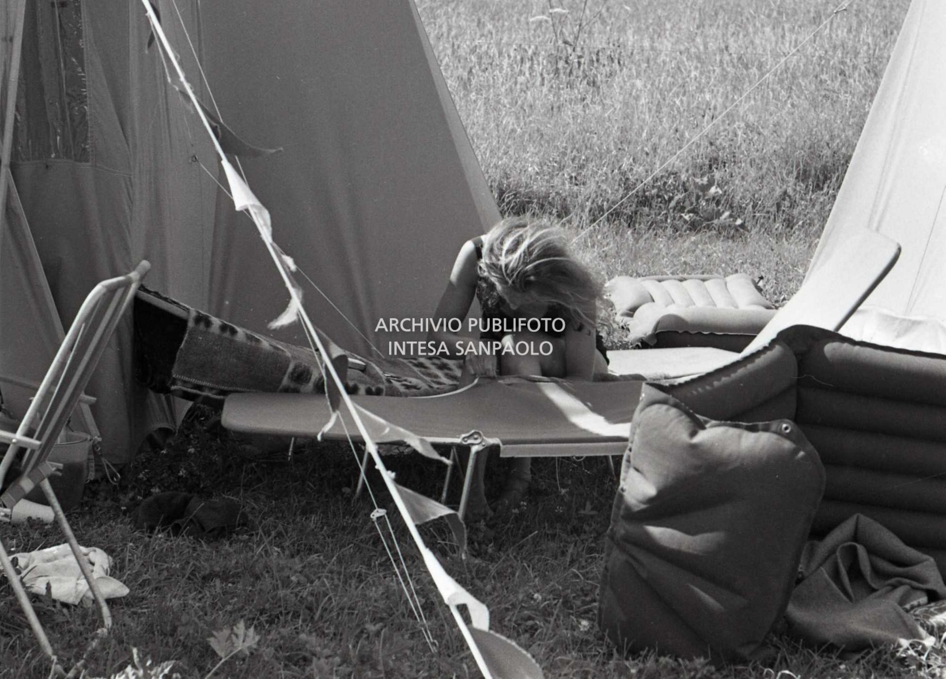 Turista in campeggio a Cortina d'Ampezzo sistema una brandina tra le tende