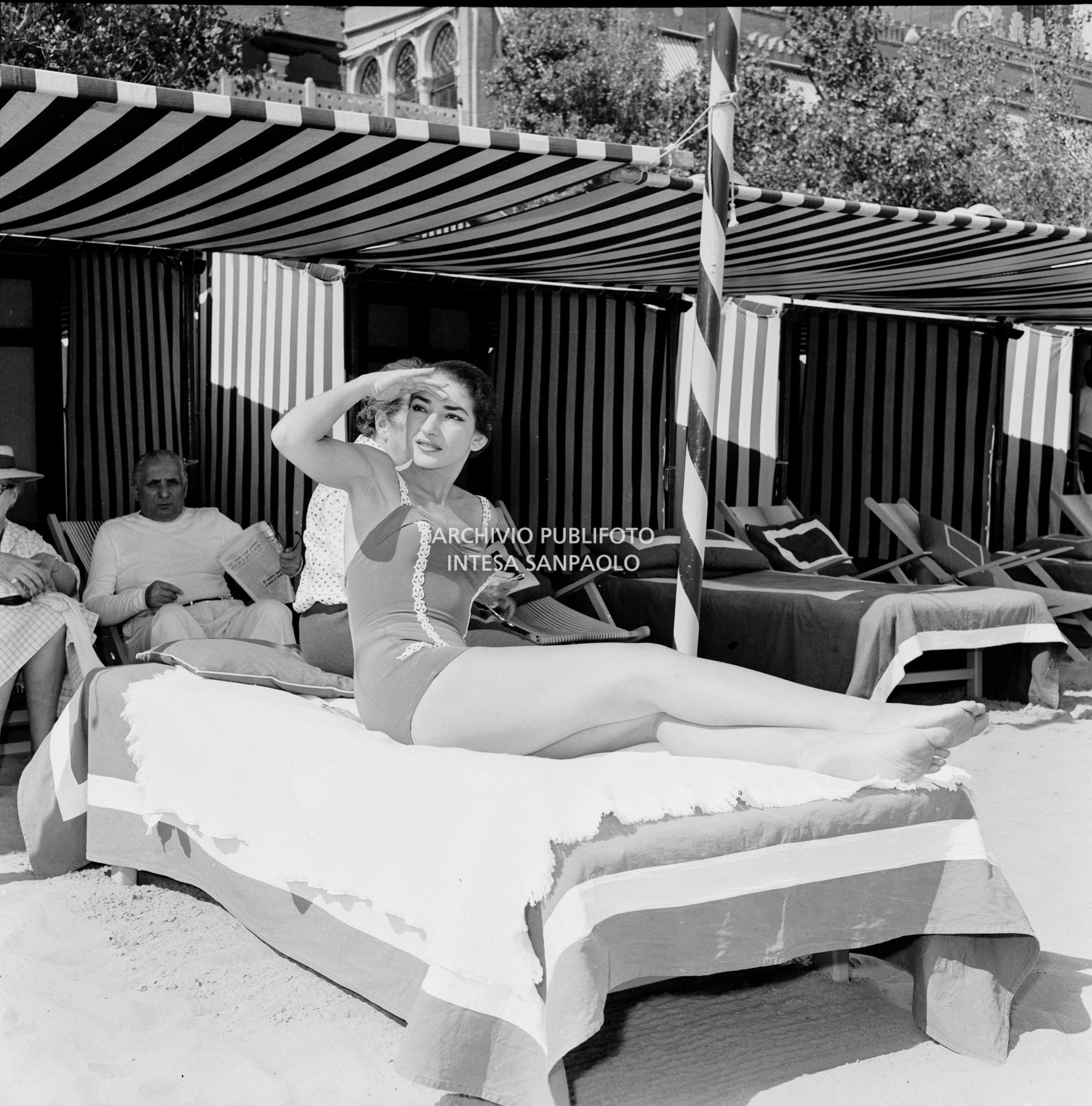 La soprano Maria Callas in costume da bagno sdraiata su un lettino al Lido di Venezia