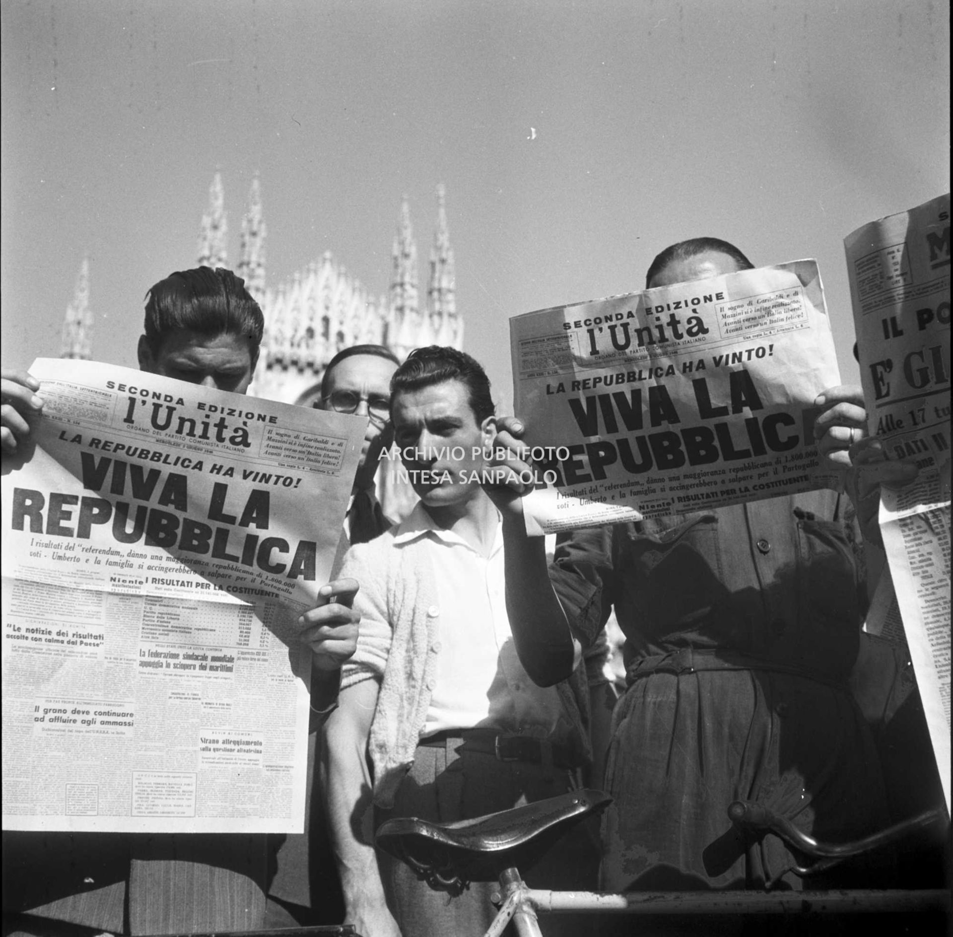 Uomini, in piazza del Duomo a Milano, leggono la seconda edizione del quotidiano l'Unità che titola: "La Repubblica ha vinto. Viva la Repubblica"