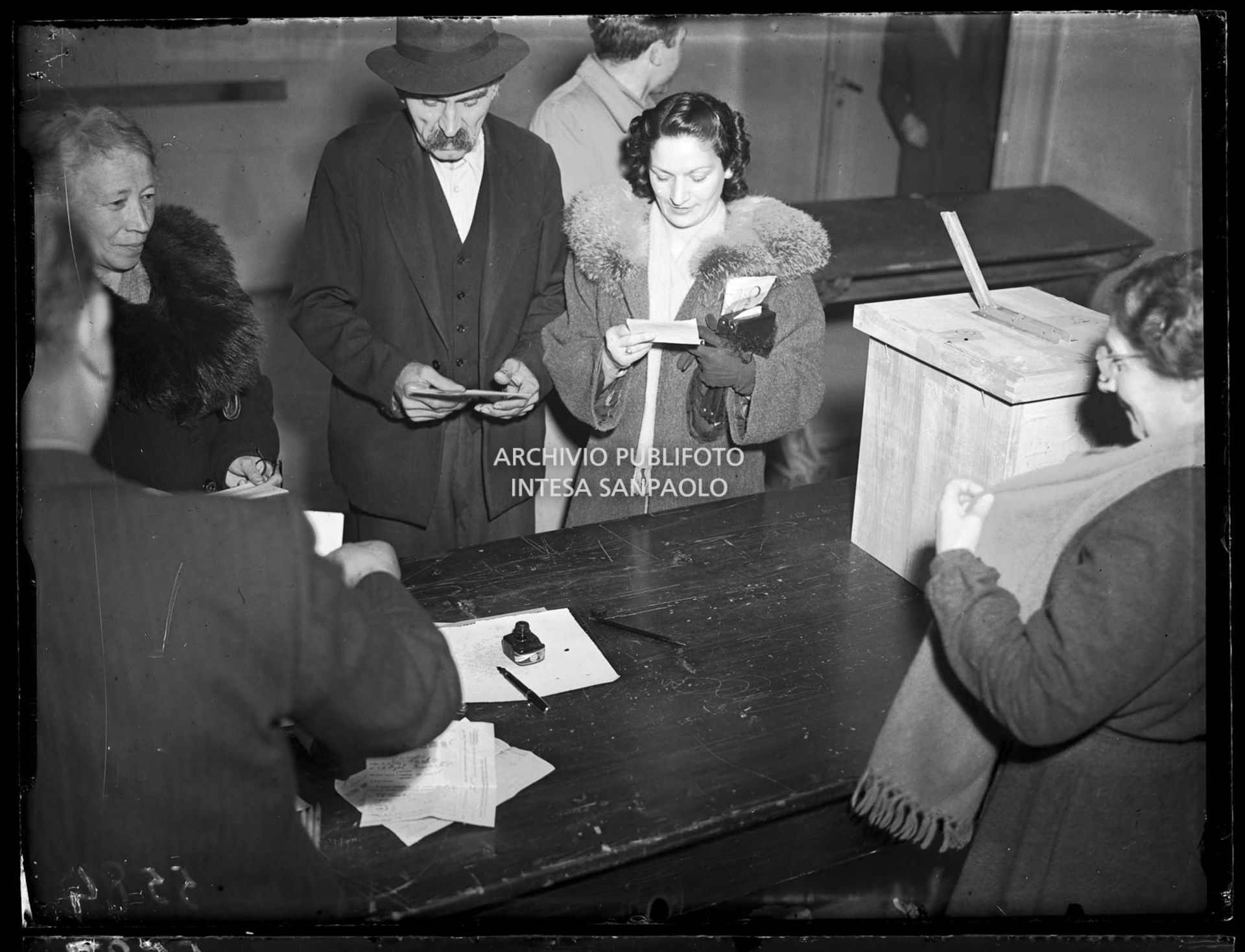 Due donne e un uomo al seggio elettorale si apprestano a votare in occasione delle elezioni comunali a Saronno, le prime elezioni a suffragio universale in Italia