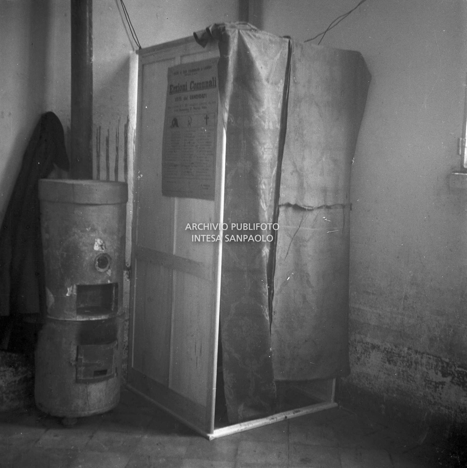 Cabina elettorale e stufa in un seggio nel Lodigiano allestito per le elezioni comunali, le prime in Italia a suffragio universale