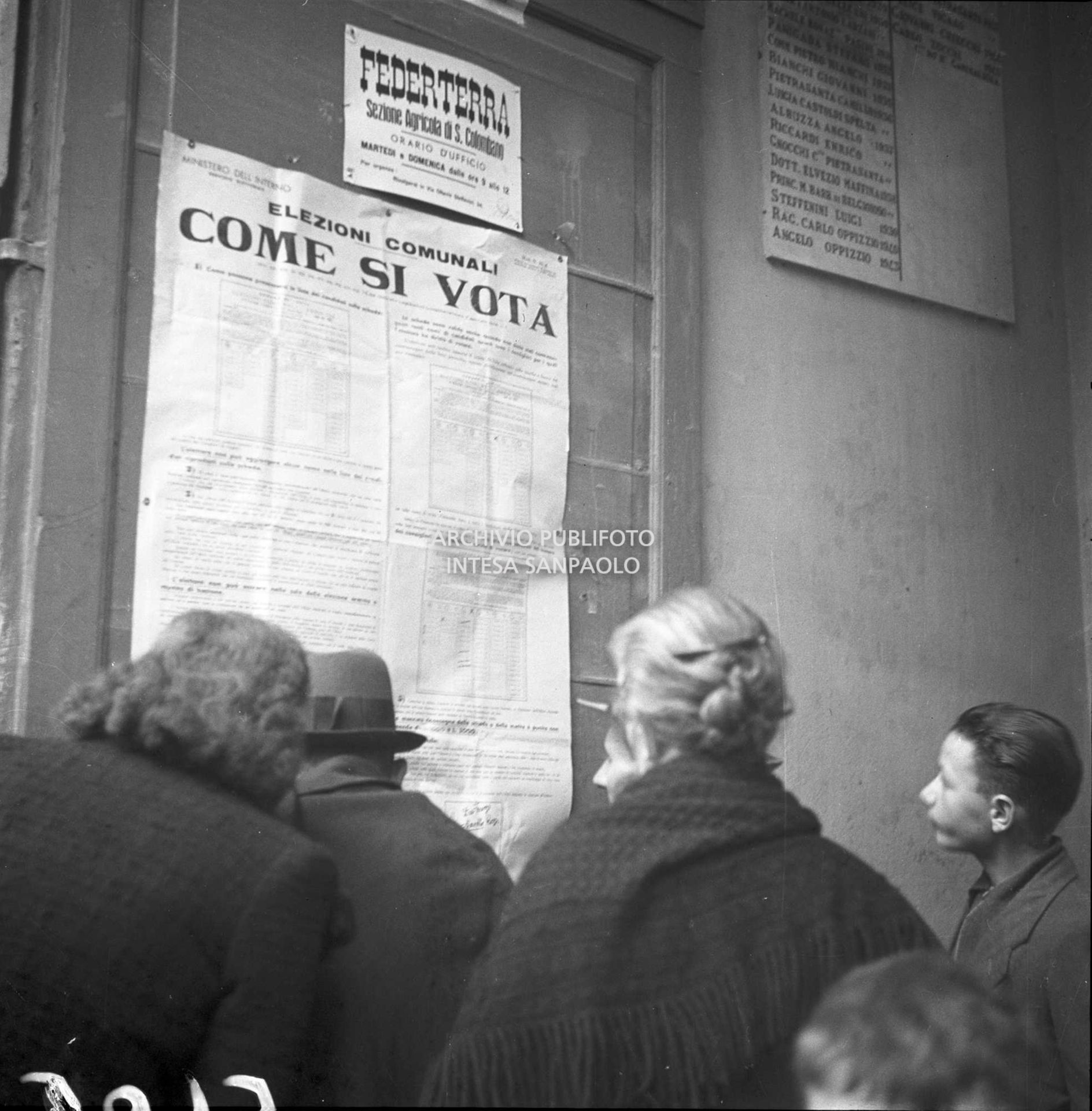 Elettori davanti al manifesto del ministero dell'Interno affisso sul muro di un edificio a San Colombano al Lambro con le modalità di voto da rispettare per le imminenti elezioni comunali