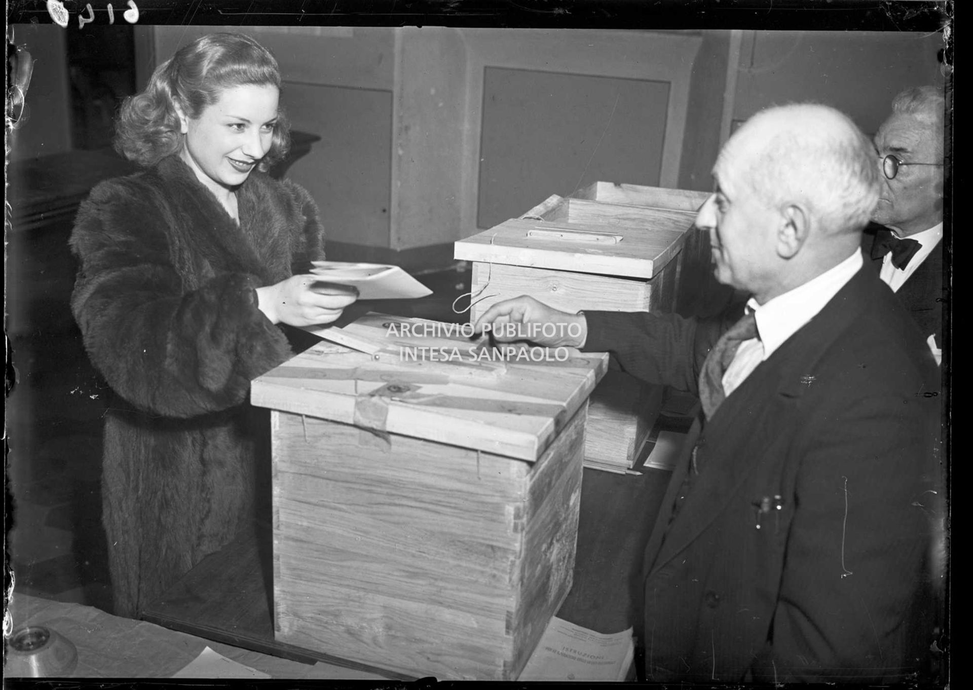 Una donna consegna i documenti per votare alle elezioni amministrative del Comune di Milano, le prime elezioni a suffragio universale in Italia