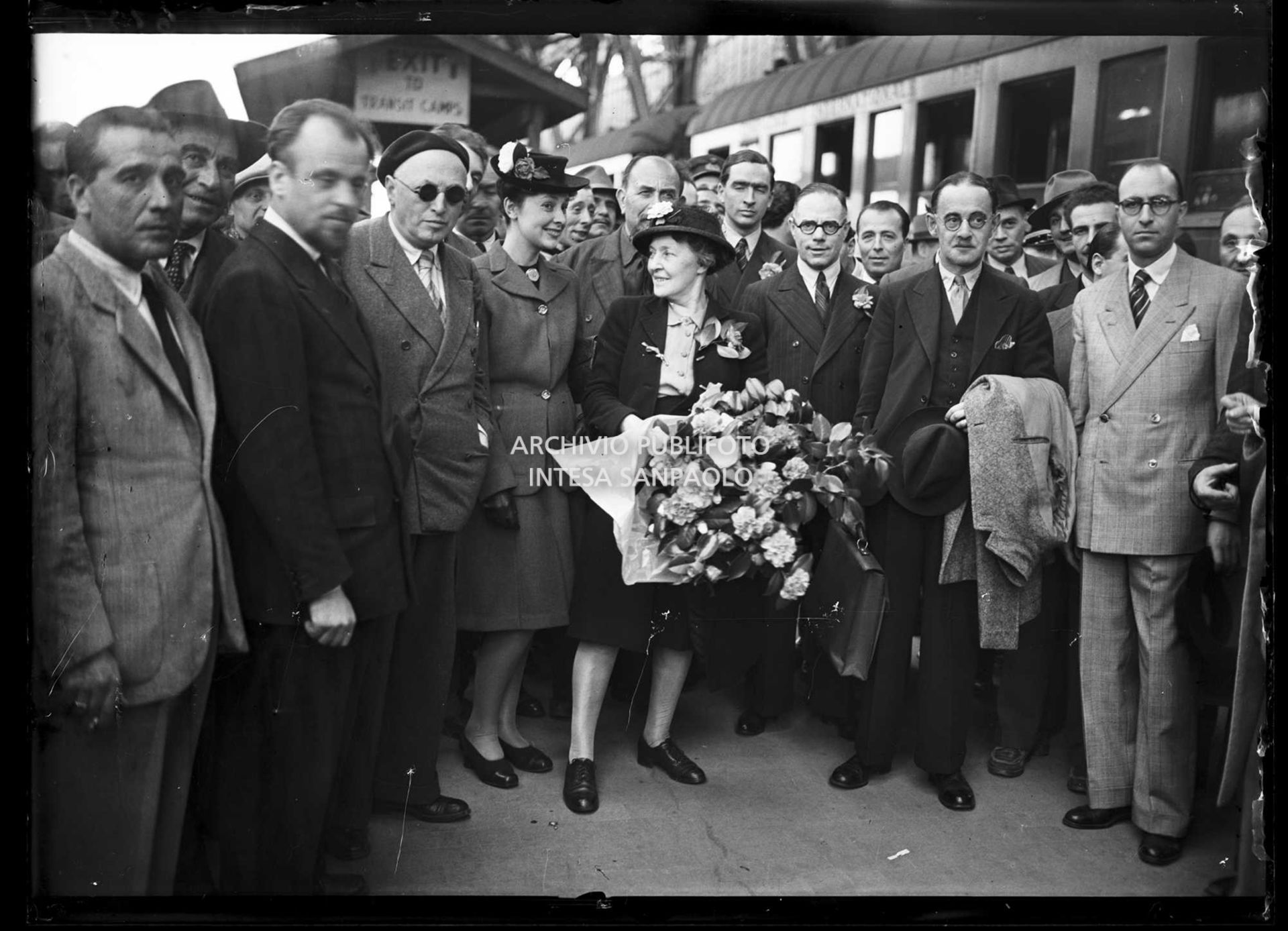 Harold Laski (secondo da destra), presidente del Partito laburista inglese, appena arrivato a Milano con Frida Kerry, sua moglie (al centro con i fiori), e Pietro Nenni (a sinistra con gli occhiali da sole)