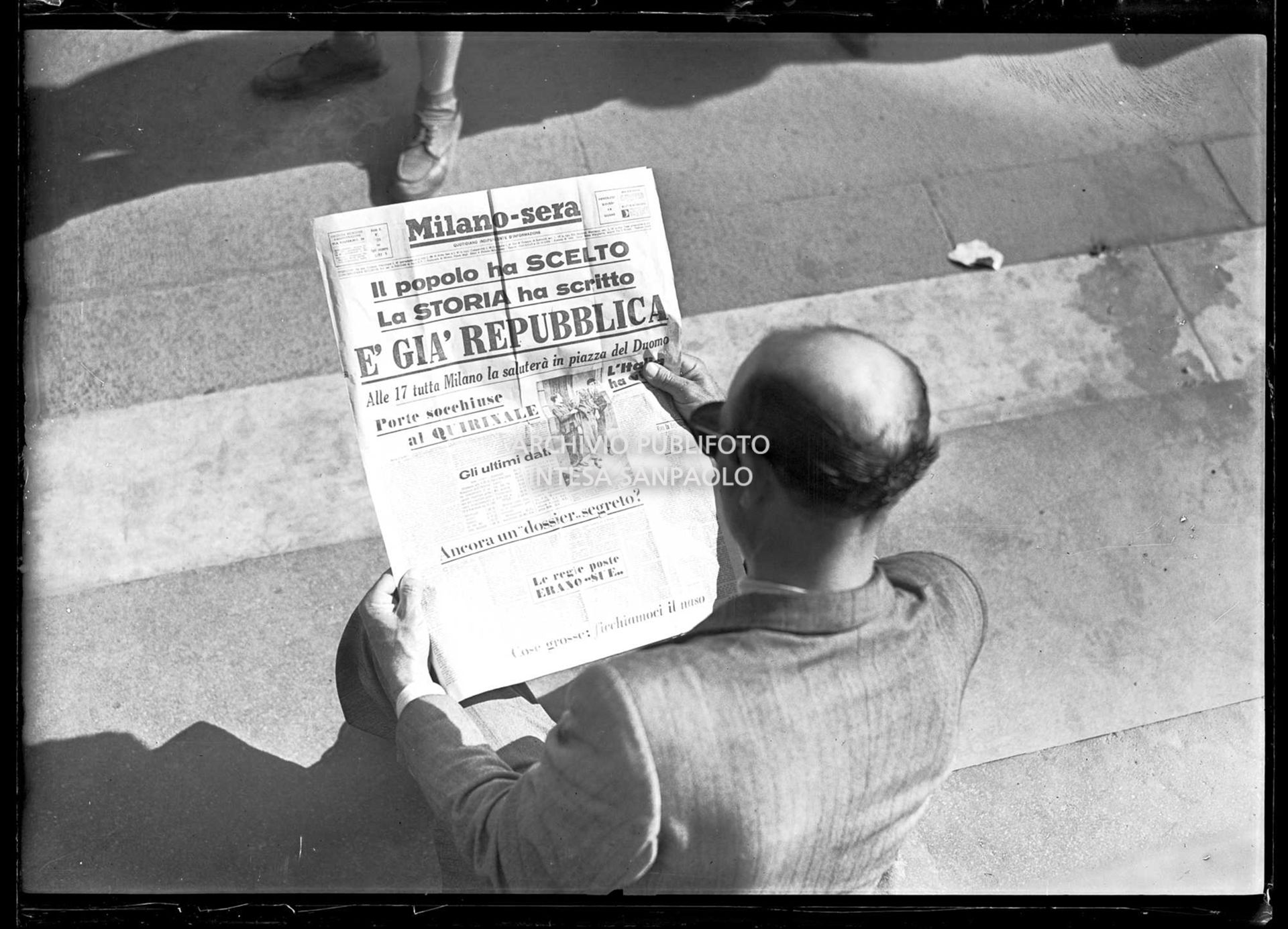 Un uomo ripreso di spalle legge il quotidiano Milano-Sera che titola: "Il popolo ha scelto. La storia ha scritto. È già Repubblica"