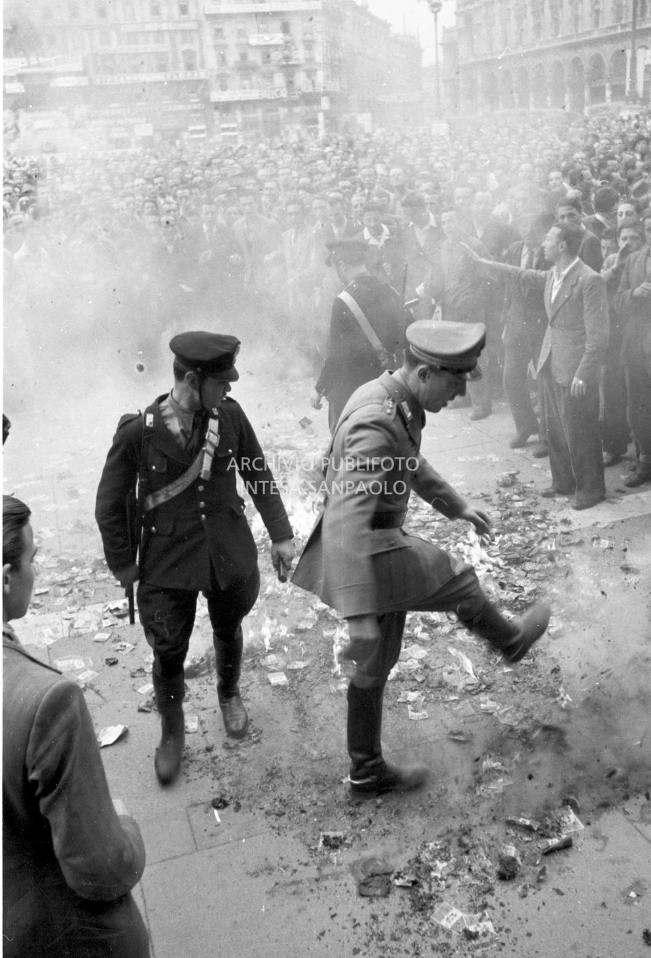 Forze dell'ordine calpestano volantini monarchici dati alle fiamme dalla folla accorsa a manifestare contro Umberto II in visita a Milano
