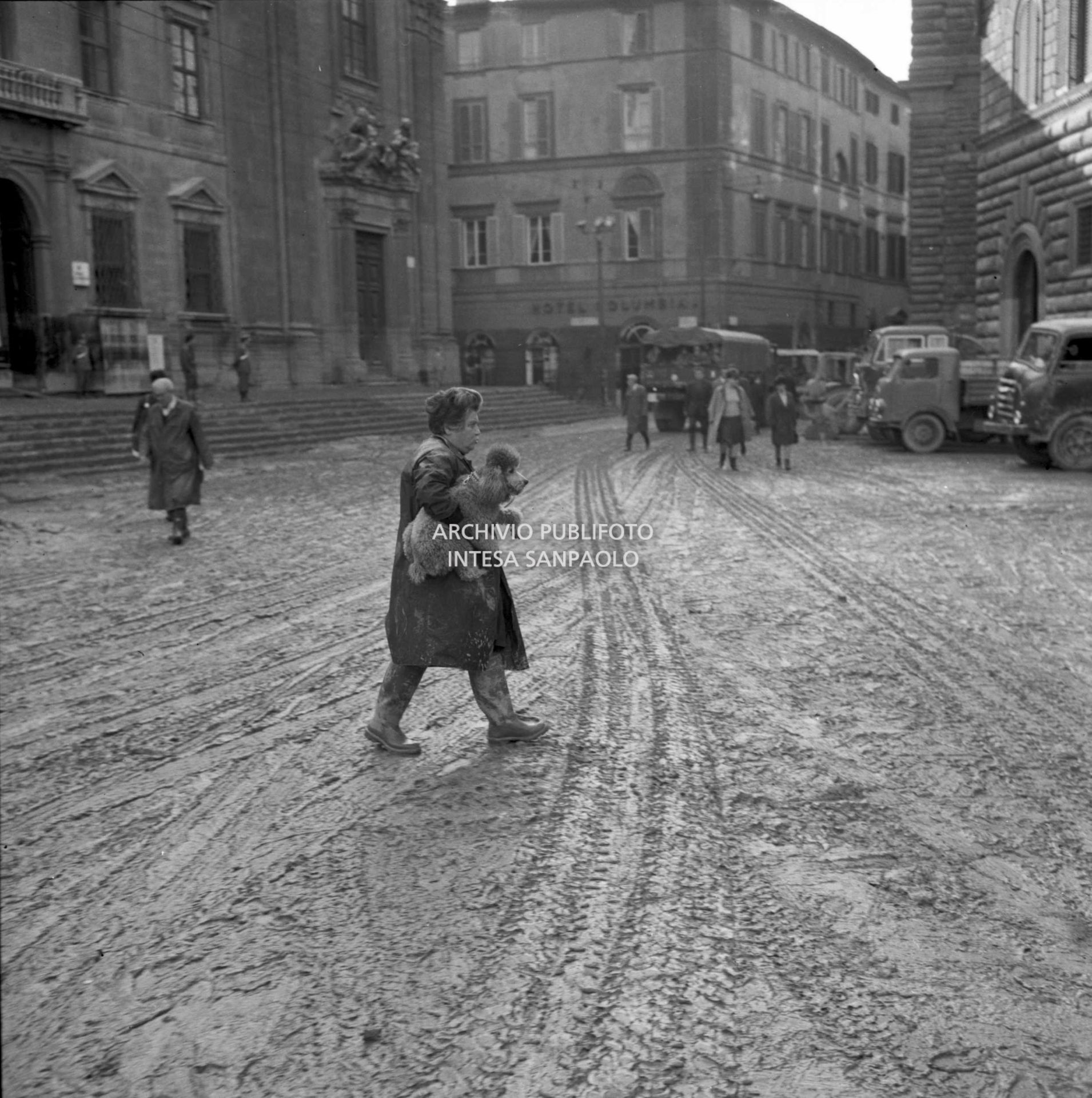 Alluvione di Firenze: una donna attraversa piazza di S. Firenze invasa dal fango con un barboncino in braccio