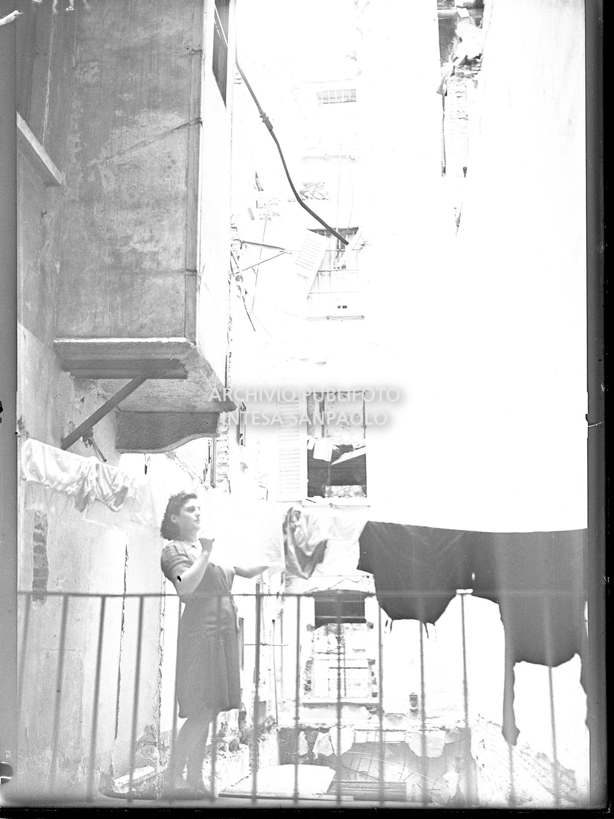 Una donna stende i panni in uno stabile danneggiato dai bombardamenti