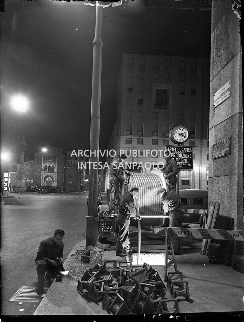 Operai della SIRTI (Società Italiana Reti Telefoniche Interurbane) posano,  di notte, cavi coassiali in piazza San Babila a Milano.