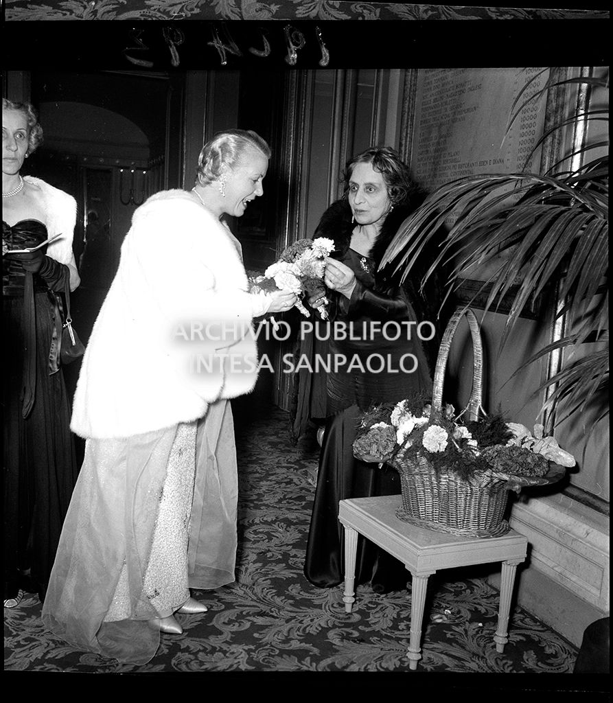 Una spettatrice in compagnia della fioraia della Scala in occasione della serata inaugurale della stagione lirica 1953-1954 del Teatro alla Scala con l'opera "La Wally", di Alfredo Catalani, diretta da Carlo Maria Giulini, con la regia di Tatiana Pavlova