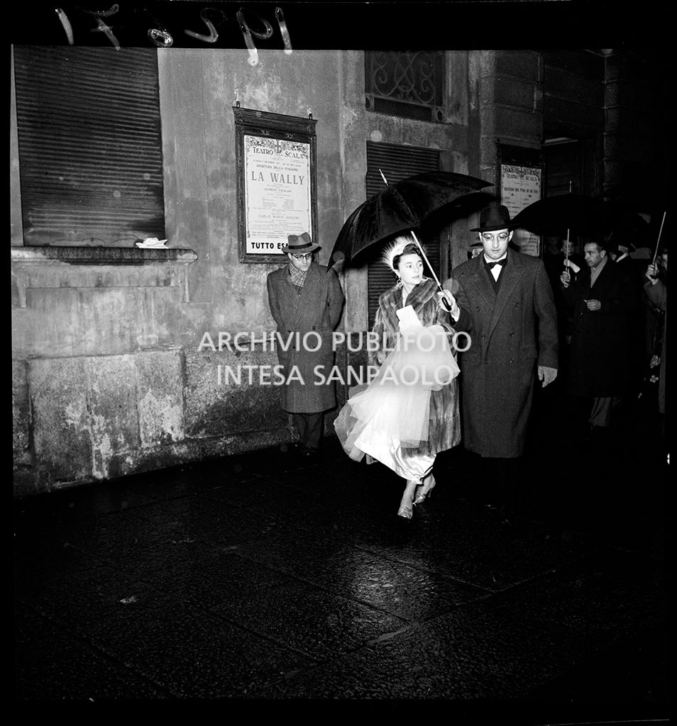 Due spettatori all'esterno del Teatro alla Scala in occasione della serata inaugurale della stagione lirica 1953-1954 con l'opera "La Wally", di Alfredo Catalani, diretta da Carlo Maria Giulini, con la regia di Tatiana Pavlova