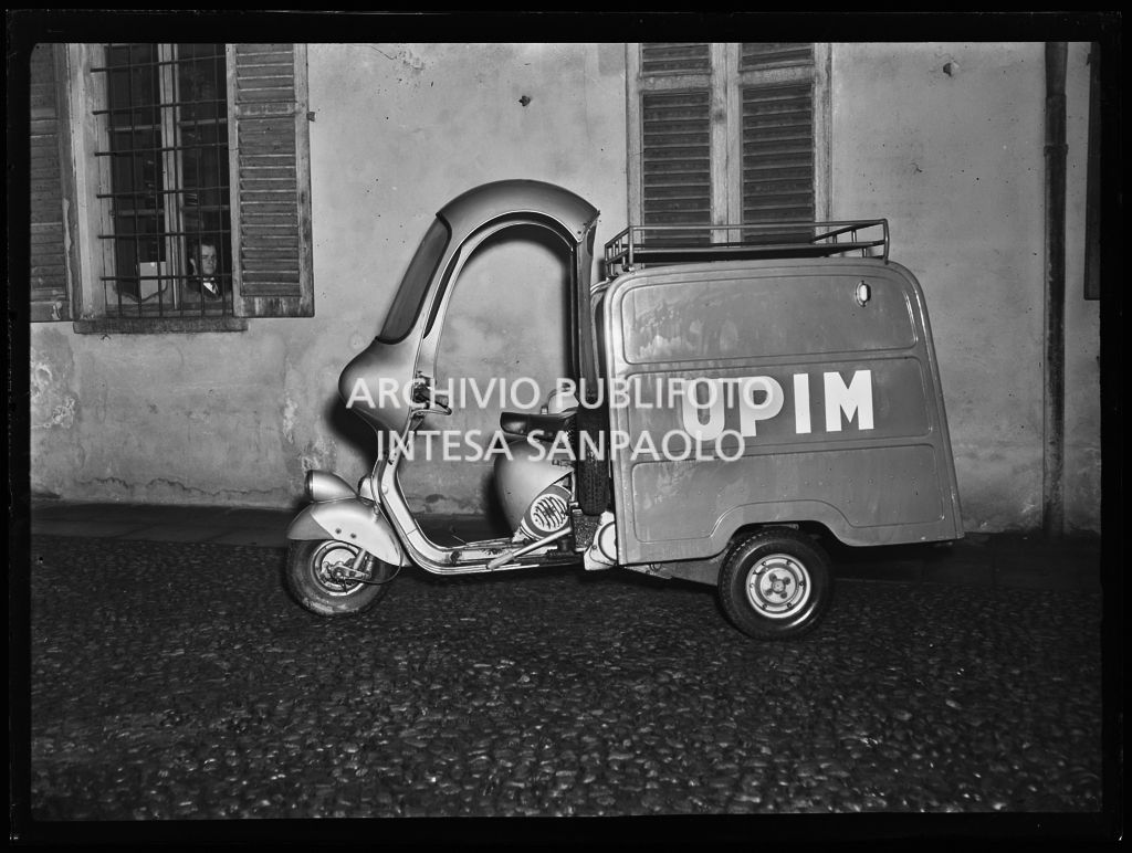 Piaggio Ape della Upim parcheggiato lungo una strada<br>196086