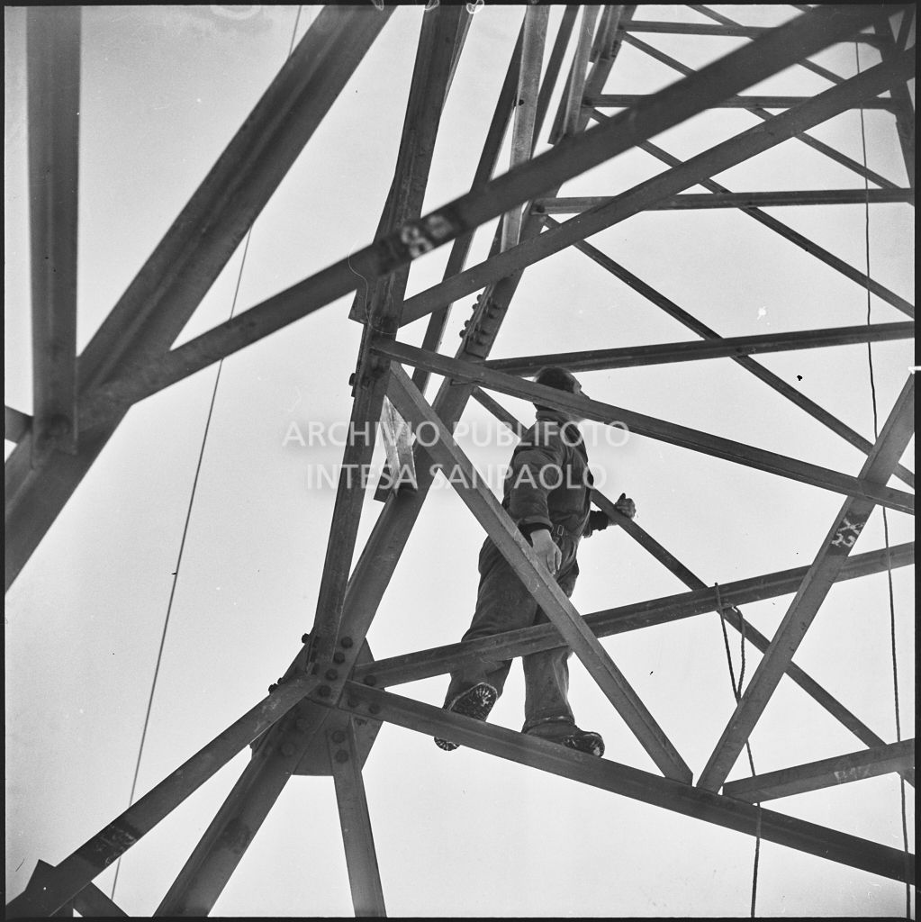 Operaio al lavoro su un traliccio dell'alta tensione per l'allacciamento dei cavi elettrici della Edison<br>196182