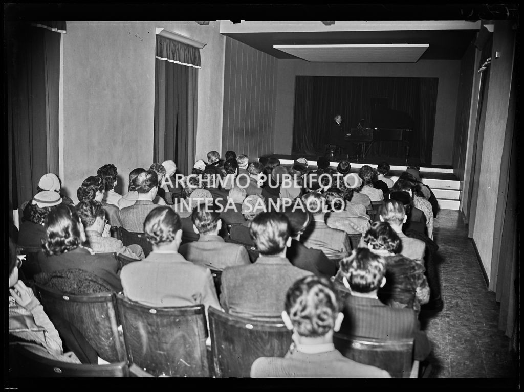 Vista sul pubblico e il palcoscenico con pianista in occasione di un concerto del Centro culturale Pirelli, organizzato in via Fabio Filzi<br>196272