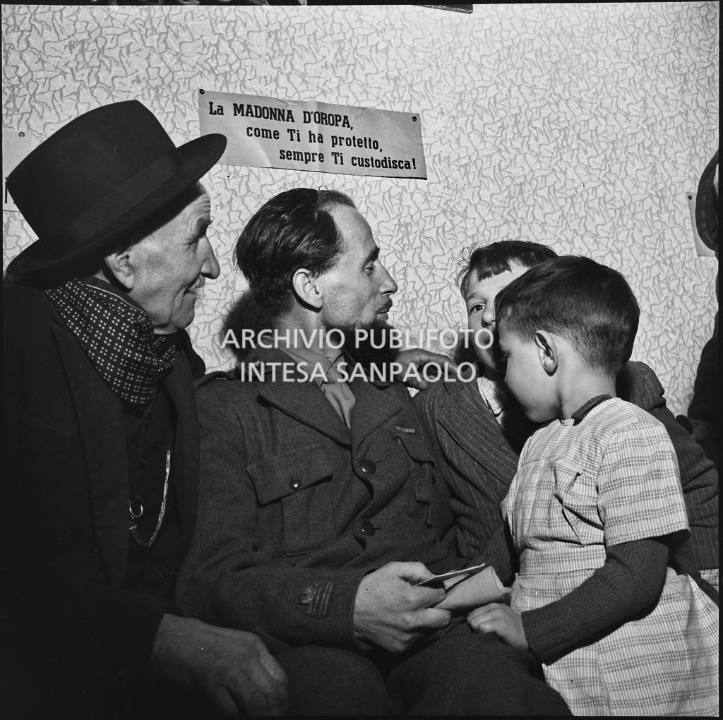 Padre Brevi di rientro in patria dopo la prigionia in Unione Sovietica, accolto da due bambini ed un anziano<br>196367