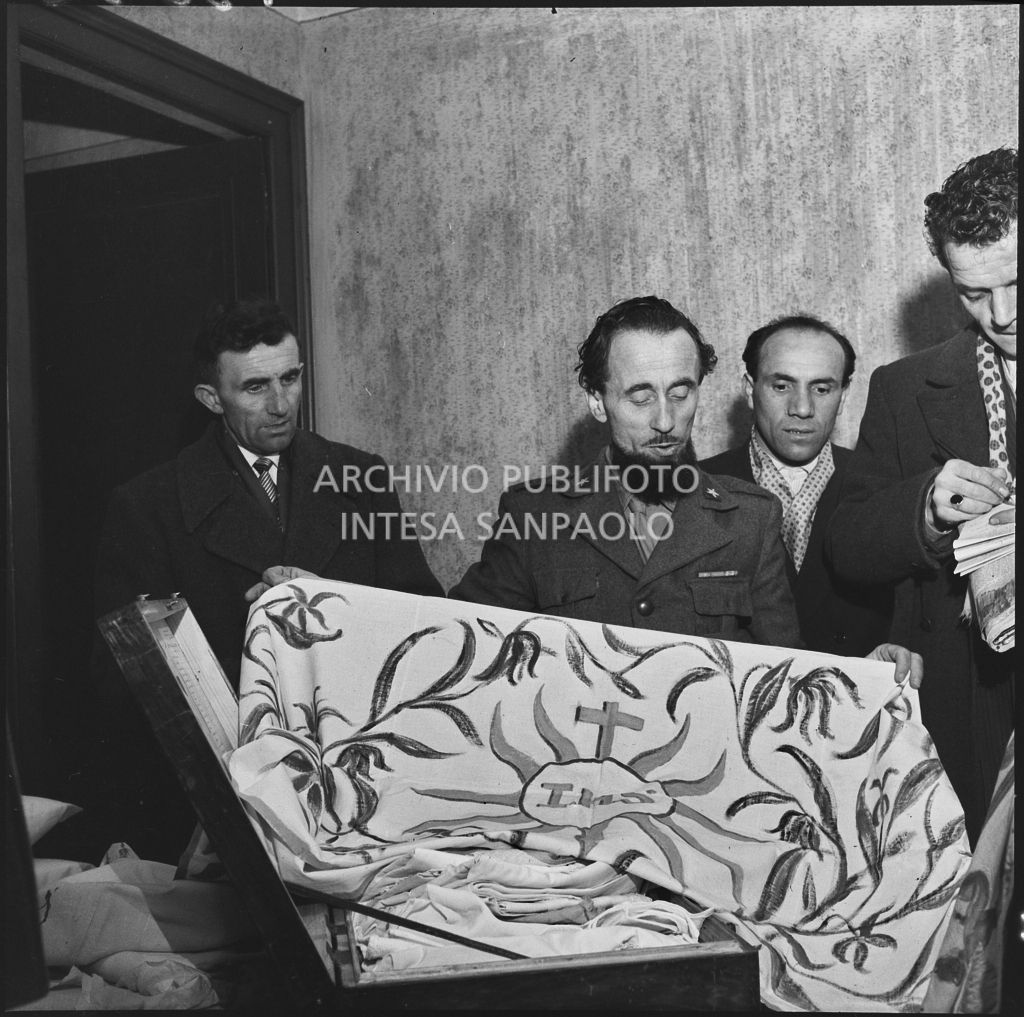 Padre Brevi, circondato da giornalisti, mostra alcuni oggetti religiosi al rientro in patria dopo la prigionia in Unione Sovietica<br>196380