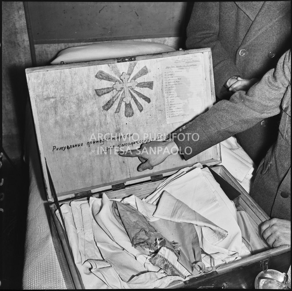 Padre Brevi, circondato da giornalisti, mostra un contenitore di oggetti religiosi con una scritta in russo<br>196381