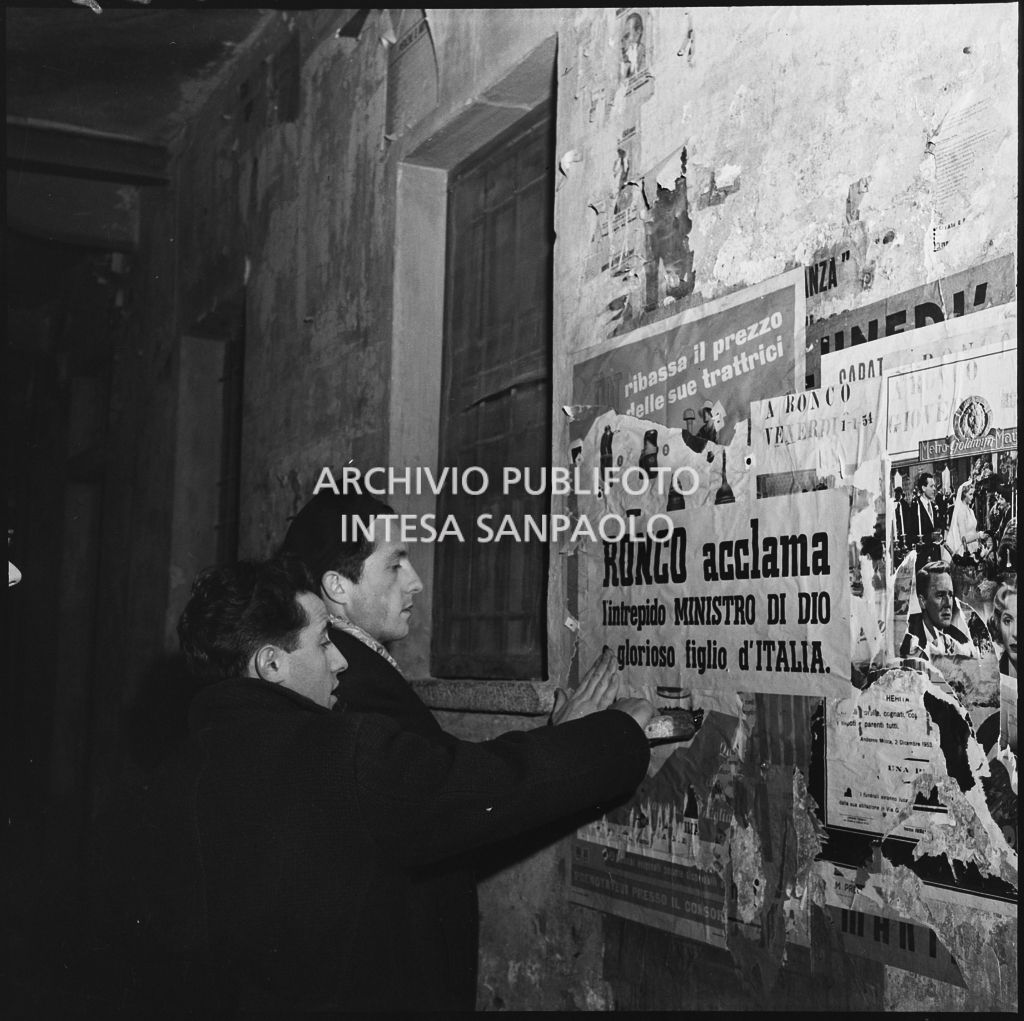 Ragazzi attaccano dei manifesti su un'abitazione di Ronco in occasione del rimpatrio dall'Unione Sovietica di alcuni ex prigionieri italiani<br>196393