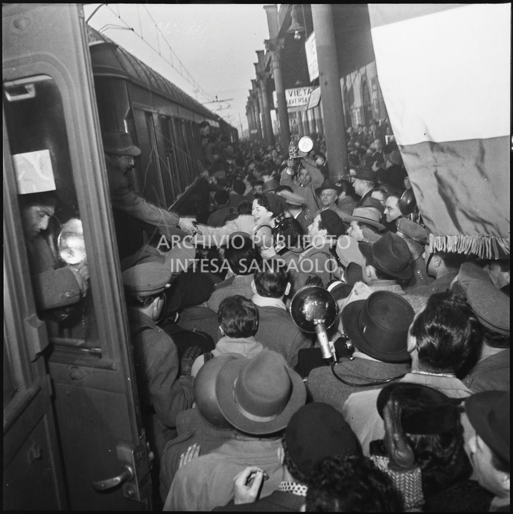 Banchina di una stazione ferroviaria gremita di gente per il ritorno in patria dall'Unione Sovietica di alcuni ex prigionieri italiani<br>196419