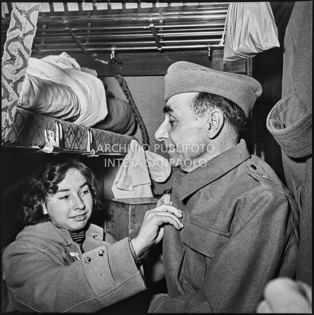 Una donna sistema il cappotto di un ex prigioniero italiano su un treno di rientro in patria<br>196441