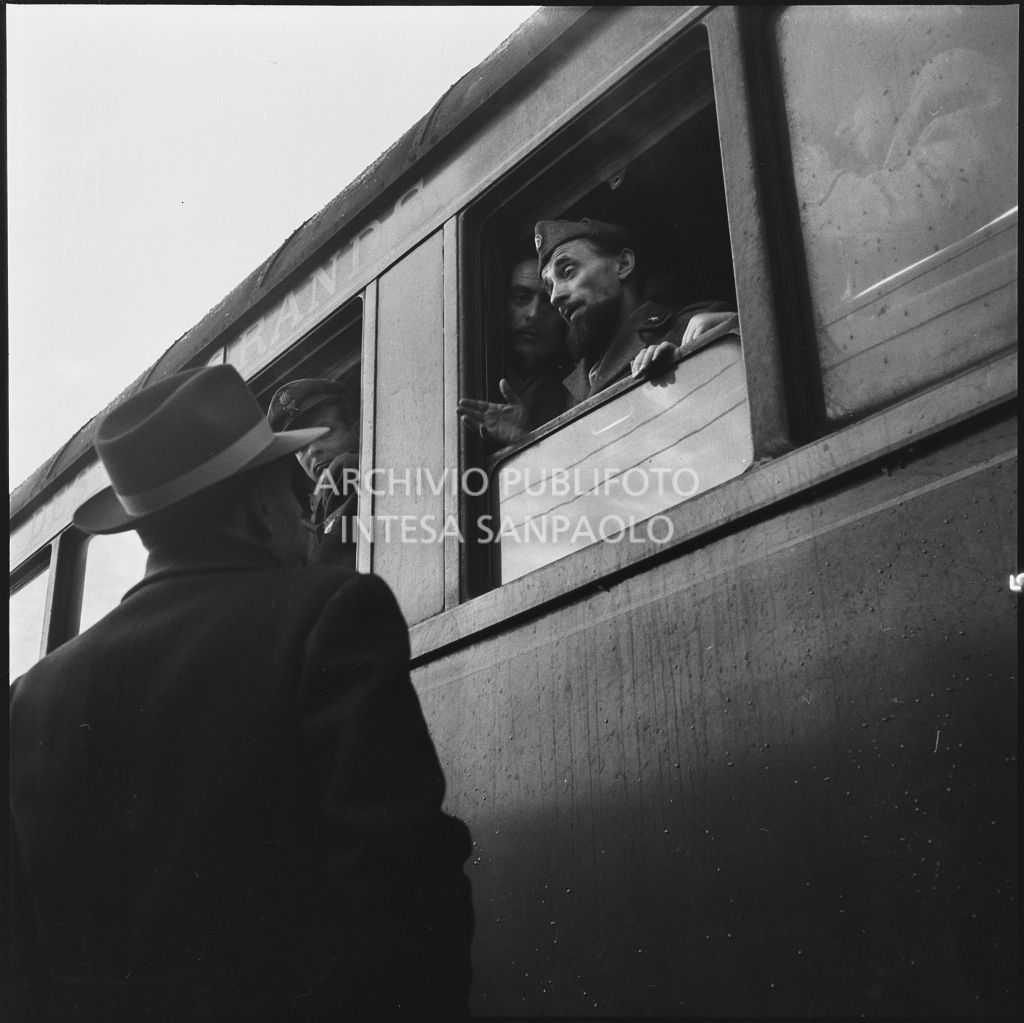 Padre Brevi di rientro dalla prigionia in Unione Sovietica discute con delle persone dal finestrino di un treno<br>196453