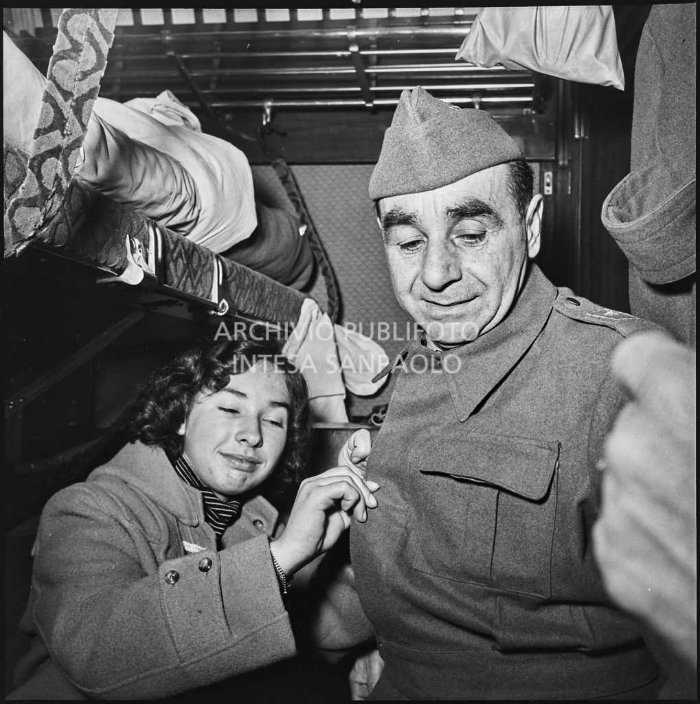 Una ragazza sistema il cappotto di un ex prigioniero italiano su un treno di rientro in patria dall'Unione Sovietica<br>196476