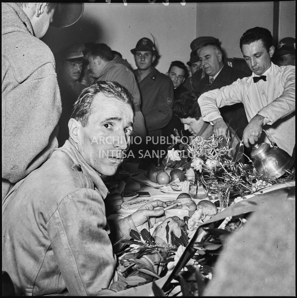 Un ex prigioniero italiano di rientro dall'Unione Sovietica fa colazione circondato da persone in festa<br>196496