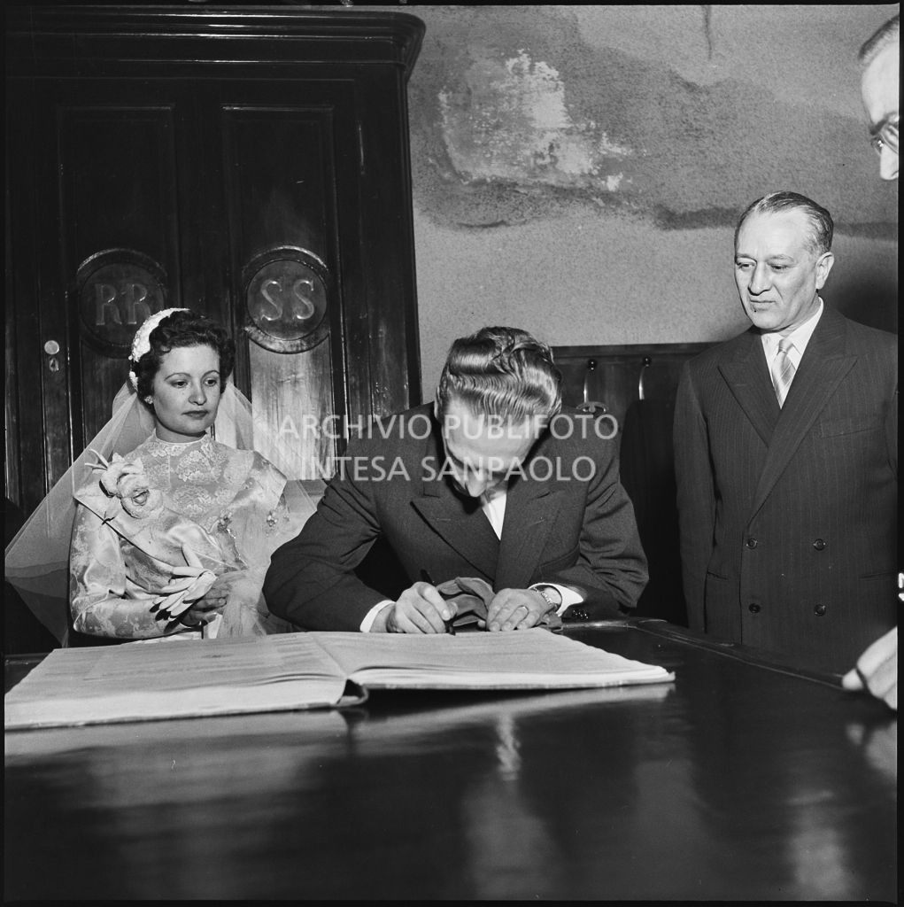 Lo sposo della signorina Cardellini nella chiesa di Santo Stefano a Sesto San Giovanni al termine della cerimonia nuziale mentre firma il registro del matrimonio<br>201782