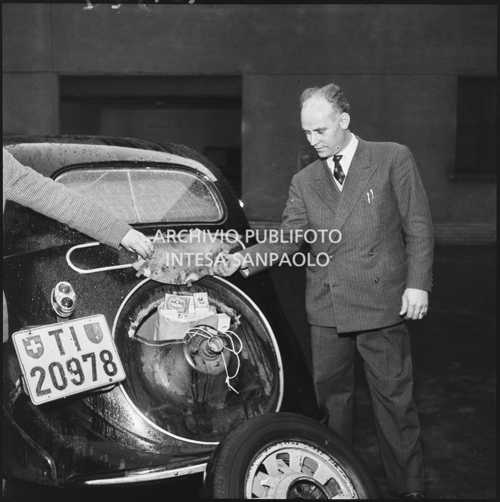 Due uomini della Polizia tributaria mostrano lo scomparto segreto di un'automobile utilizzata dai contrabbandieri di sigarette<br>201827