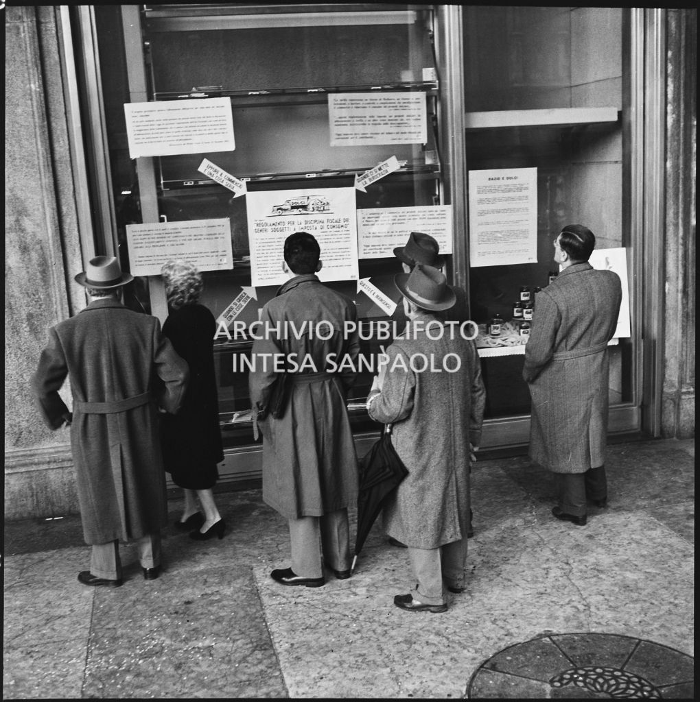 Vetrina del negozio Motta nella Galleria Vittorio Emanuele II a Milano con i manifesti del "Regolamento per la disciplina fiscale dei generi soggetti a imposta di consumo"<br>201854