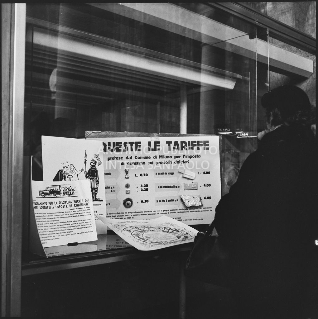 Tariffe e vignette satiriche contro i dazi previsti dal "Regolamento per la disciplina fiscale dei generi soggetti a imposta di consumo" esposti in una vetrina del negozio Motta nella Galleria Vittorio Emanuele II a Milano<br>201857