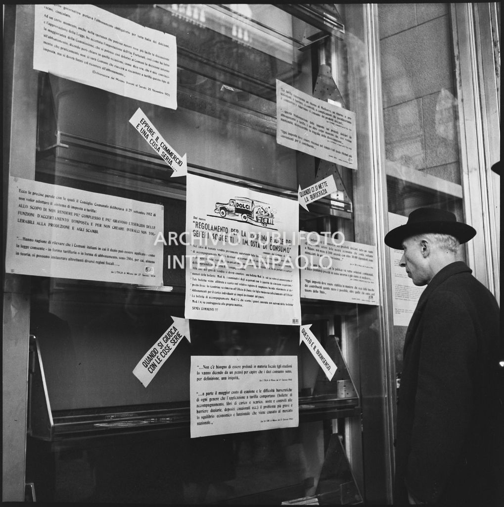Vetrina del negozio Motta nella Galleria Vittorio Emanuele II a Milano con i manifesti del "Regolamento per la disciplina fiscale dei generi soggetti a imposta di consumo"<br>201860