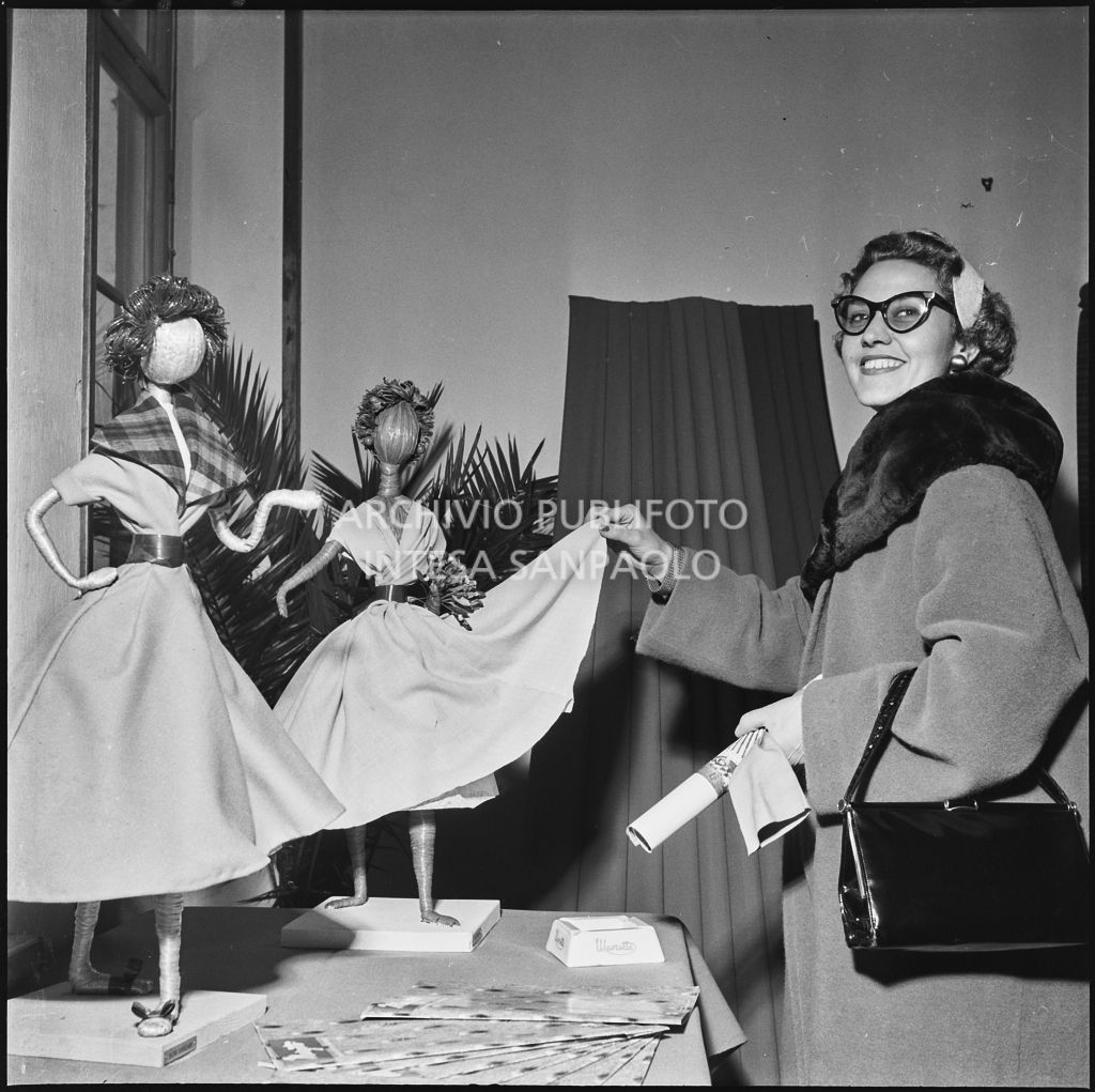 La redattrice di una rivista di moda in posa accanto a piccoli manichini in occasione della vista allo stabilimento del Lanificio Marzotto a Manerbio<br>201982