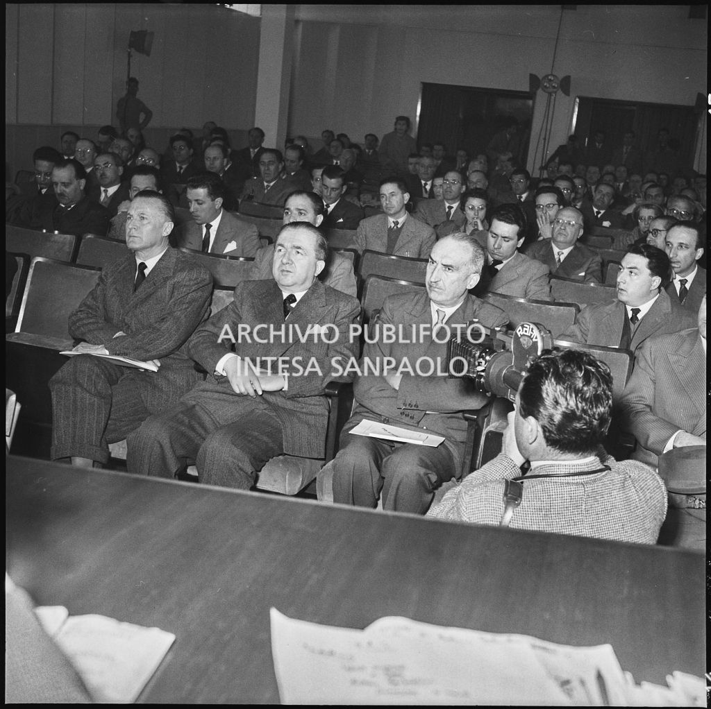 L'onorevole Giuseppe Pella tra gli spettatori del convegno "Human relations" nella sala Puricelli della Fiera campionaria di Milano del 1954. In primo piano un cameraman della Rai<br>210804