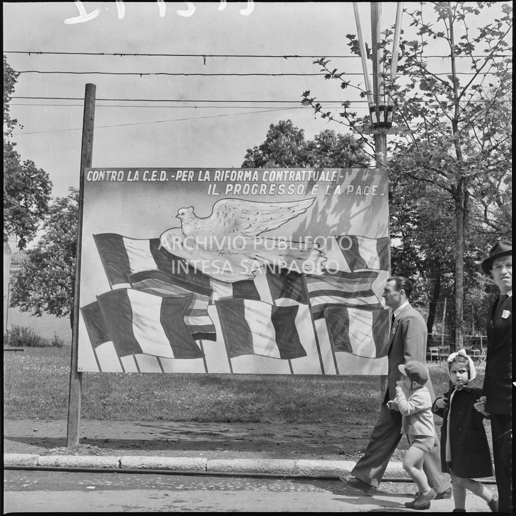 Due uomini, tenendo per mano dei bambini, passano davanti ad un pannello descrittivo allestito in occasione della Festa del 1°maggio ai Giardini Margherita di Bologna<br>212197
