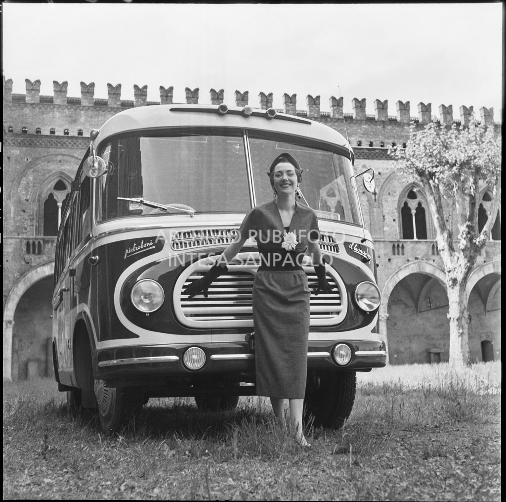 Indossatrice con le creazioni della Marzotto in posa davanti a un autobus nel giardino del castello di Pavia<br>212357