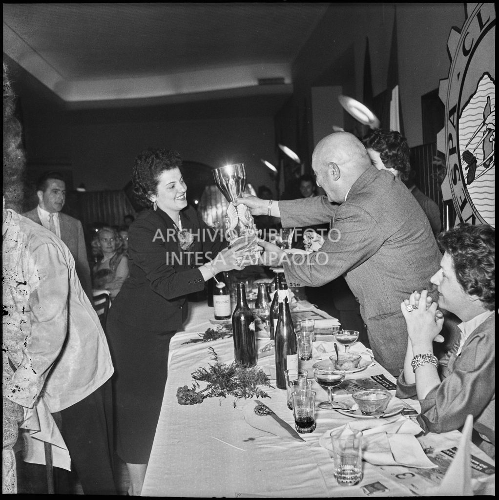 Un uomo consegna il premio ad una delle vincitrici della terza edizione dell'Audax internazionale vespistico femminile durante il banchetto organizzato del Vespa Club Milano<br>215327