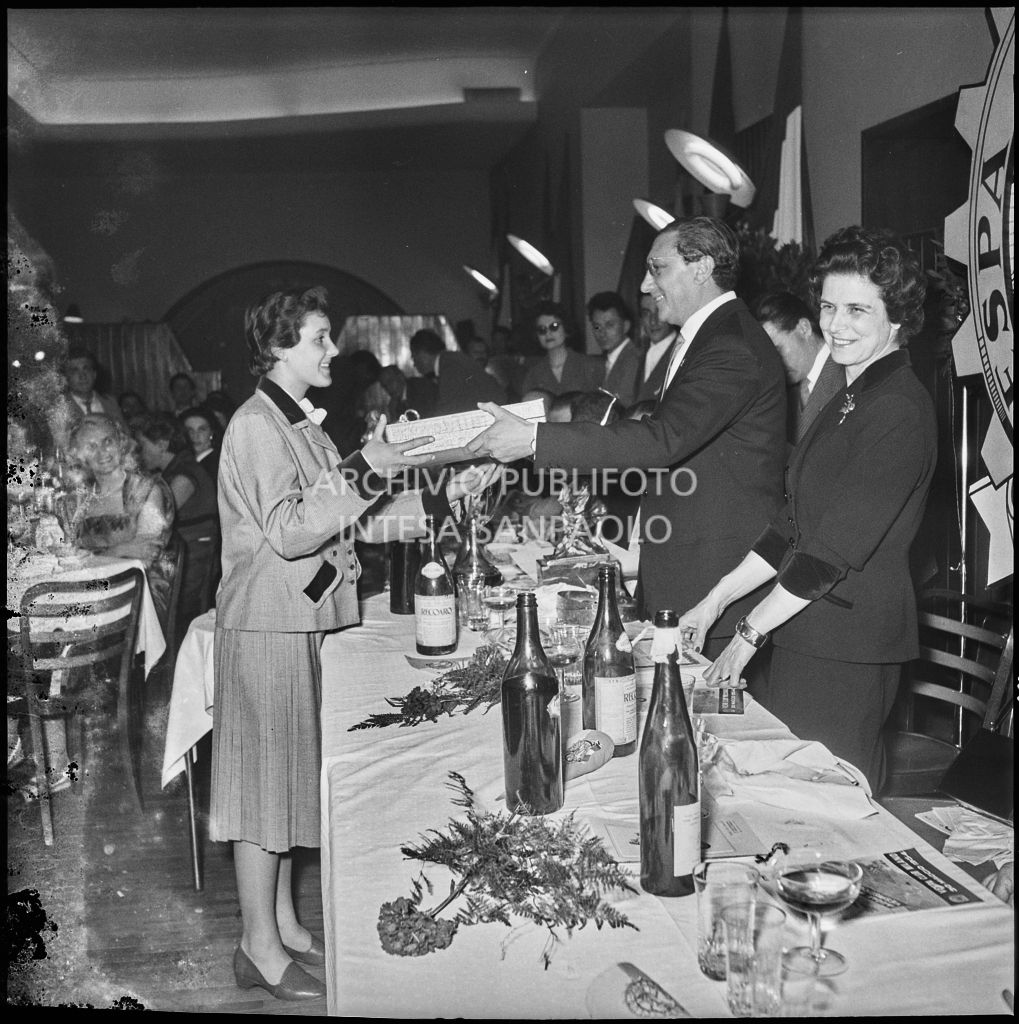 Il presidente del Vespa Club Milano Renato Tassinari consegna un pacco ad una delle vincitrici della terza edizione dell'Audax internazionale vespistico femminile durante il banchetto organizzato del Vespa Club Milano<br>215339